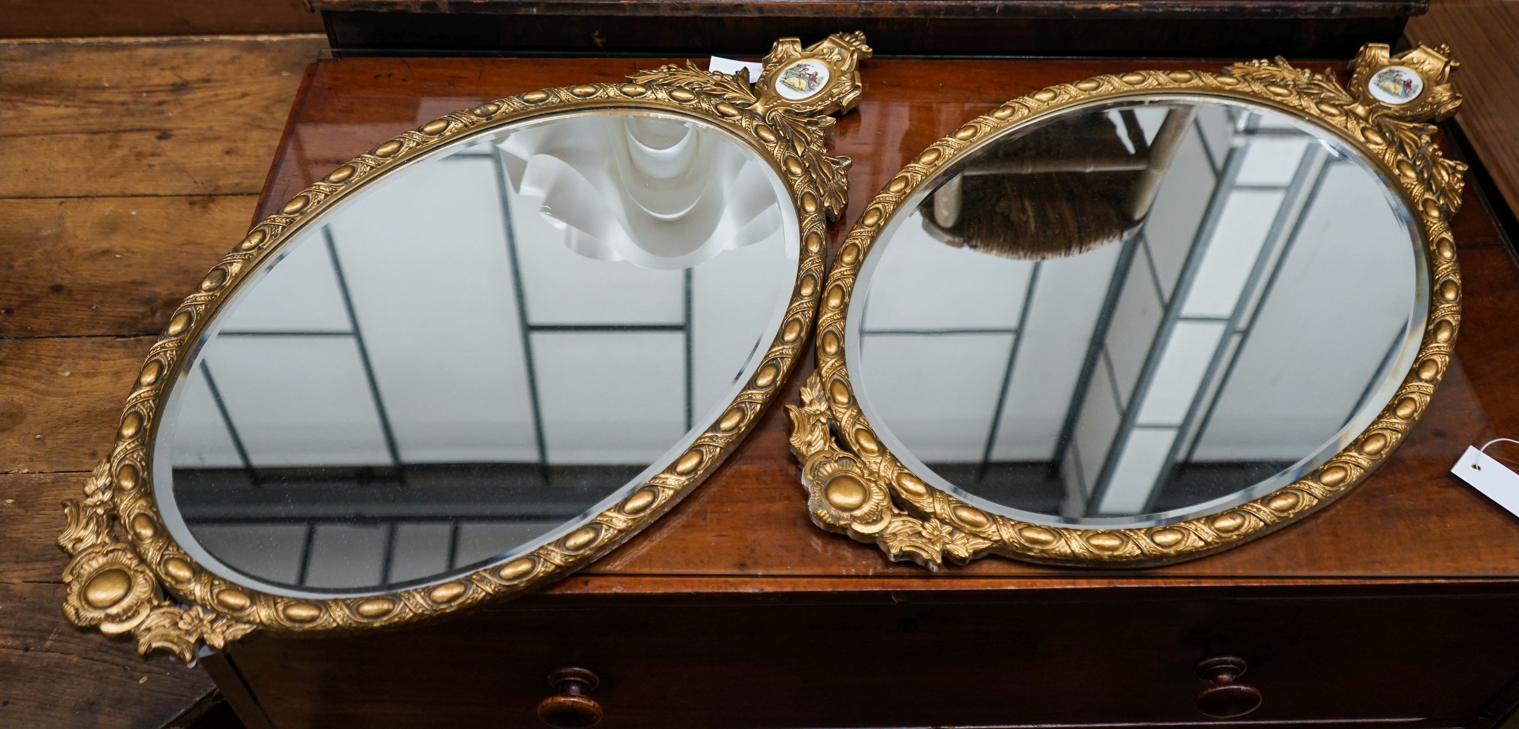 A pair of oval gilt framed wall mirrors inset porcelain plaques, width 42cm, height 78cm